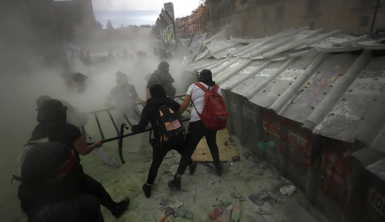 Demonstran menyerang barikade yang melindungi Istana Nasional selama pawai untuk memperingati Hari Perempuan Internasional dan memprotes kekerasan gender di Mexico City, Meksiko, Senin (8/3/2021). Hari Perempuan Internasional diperingati setiap tanggal 8 Maret. (AP Photo/Rebecca Blackwell)