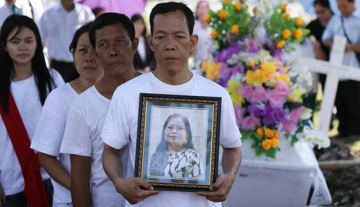 Keluarga korban bom gereja Surabaya membawa foto Martha Djumani pada pemakaman di komplek Taman Makam Keputih, Surabaya, Rabu (16/5). Martha merupakan korban bom bunuh diri di Gereja Pantekosta Pusat Surabaya Minggu (13/5) lalu. (AP/Achmad Ibrahim)