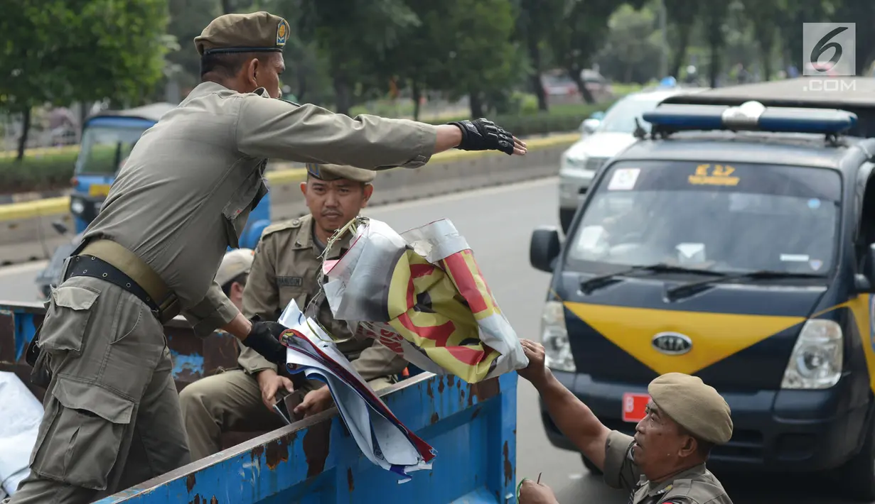 Petugas Satpol PP menertibkan APK Pemilu 2019 di Kawasan Jalan Pemuda, Jakarta, Rabu (13/3). APK Pemilu 2019 yang terpasang pada JPO dibersihkan hal tersebut mengganggu dan melanggar aturan pemasangan dari komisi Pemilihan umum. (merdeka.com/Imam Buhori)