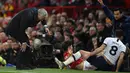 Pelatih Jose Mourinho kesakitan saat tertendang pemain Tottenham Hotspur, Harry Winks dan pemain Manchester United, Daniel James pada pertandingan lanjutan Liga Inggris di Old Trafford, Rabu (4/12/2019). Tottenham kalah tipis atas MU 2-1. (AFP Photo/Oli Scarff)