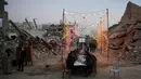 Di lokasi pengungsian, warga mencoba menghidupkan suasana Ramadan dengan kreativitas, seperti membuat lentera (fanous) dari kaleng bekas atau kain bantuan. Tampak dalam foto, warga Palestina duduk di meja panjang di tengah reruntuhan bangunan yang hancur untuk berbuka puasa bersama, selama bulan suci Ramadan di Khan Younis, Jalur Gaza, Kamis 19 Februari 2026. (AP Photo/Abdel Kareem Hana)