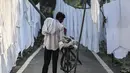 Seorang pekerja meletakkan pakaian yang sudah dicuci untuk dikeringkan di binatu terbuka, yang secara lokal disebut 'Dhobi Ghat' di New Delhi, India pada 14 Maret 2022. Dhobi Ghat adalah tempat yang menyediakan layanan cuci dengan cara tradisional. (Money SHARMA / AFP)
