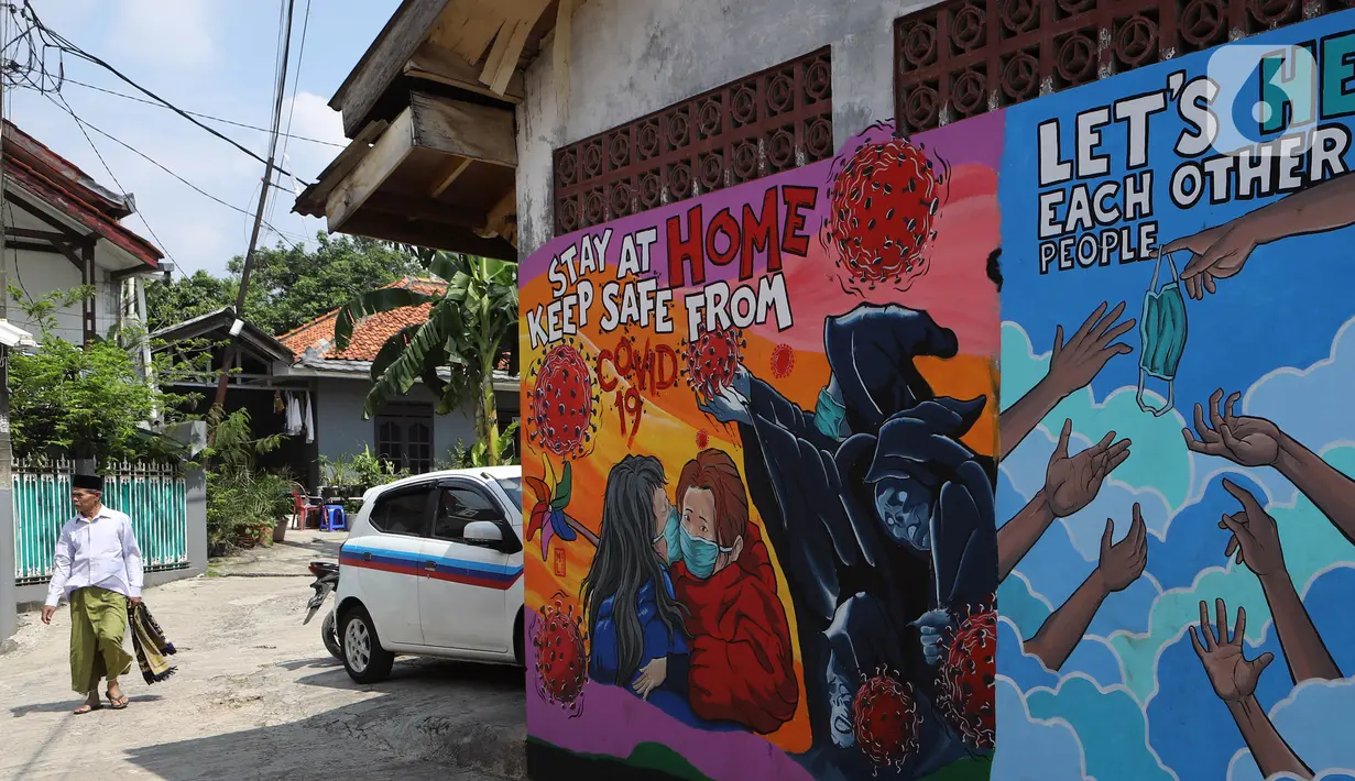 Warga berjalan di depan mural bertema virus corona COVID-19 yang menghiasi dinding rumah di kawasan Pangkalan Jati Baru, Depok, Jawa Barat, Selasa (2/6/2020). Mural bertulis ‘Stay At Home, Keep Safe From COVID-19’ itu untuk mengingatkan warga akan bahaya COVID-19. (Liputan6.com/Johan Tallo)