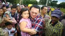 Cagub DKI Jakarta, Basuki T Purnama mengendong seorang anak saat menghadiri acara "Bersyukur Jakarta", Jumat (20/1). Dalam acara yang berbentuk bakti sosial dan pasar murah tersebut, terdapat hiburan dan permainan anak. (Liputan6.com/Immanuel Antonius)