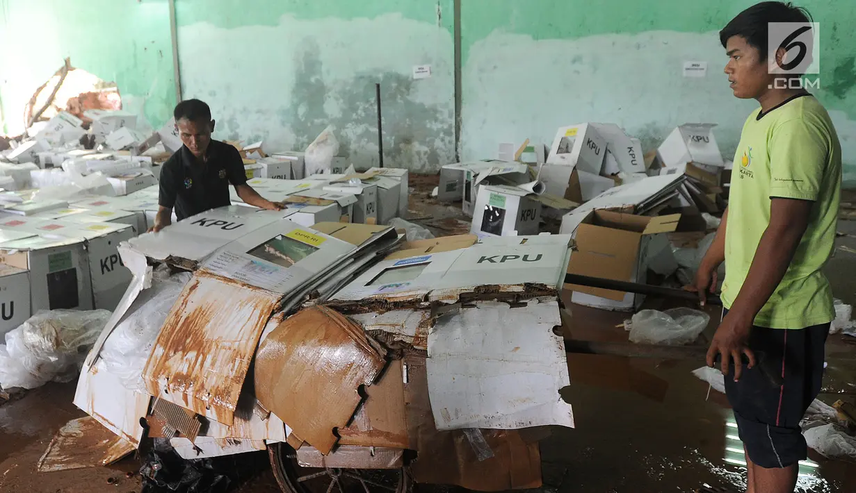 Pekerja memindahkan kotak suara kardus yang sebagian rusak terendam banjir di gudang tempat penyimpanan logistik di Kecamatan Ciseeng, Kabupaten Bogor, Senin (15/4). Lebih dari 600 kotak suara rusak akibat tembok gudang jebol diterpa hujan lebat dan angin kencang semalam. (merdeka.com/Arie Basuki)