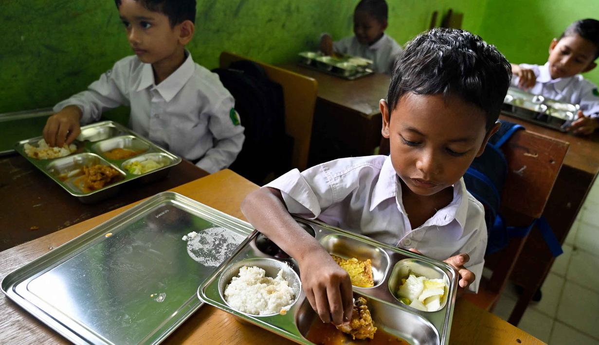 Beberapa siswa menikmati makanan yang disediakan lewat program pemerintah Indonesia, Makan Bergizi Gratis (MBG), di sebuah sekolah dasar di Darul Kamal, Provinsi Aceh pada Senin 13 Oktober 2025. (CHAIDEER MAHYUDDIN/AFP)