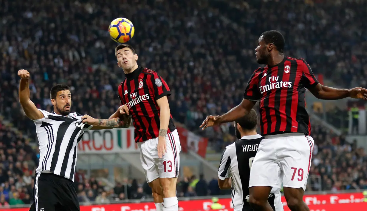 Pemain AC Milan, Alessio Romagnoli menyundul bola yang berusaha direbut pemain Juventus, Sami Khedira pada lanjutan Serie A Italia di Stadion San Siro, Sabtu (28/10). Lewat Gonzalo Higuain, Juve memetik kemenangan dua gol tanpa balas. (AP/Antonio Calanni)