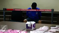 Tersangka AR yang menjadi kurir dihadirkan dalam rilis di kantor BNN, Jakarta, Selasa (27/10/2015). BNN mengamankan empat tersangka kasus narkoba dengan barang bukti 1000 butir pil ekstasi, dua diantaranya merupakan oknum TNI. (Liputan6.com/Yoppy Renato)