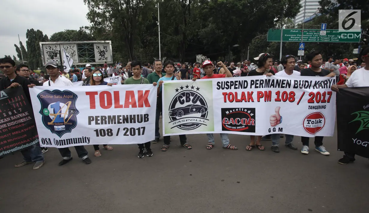 Demonstran driver online membentangkan spanduk dalam unjuk rasa  di depan Istana Negara, Jakarta, Rabu (14/2). Massa meneriakkan suaranya meminta Menteri Perhubungan Budi Karya, untuk menghapus Permenhub 108 tahun 2017. (Liputan6.com/Arya Manggala)