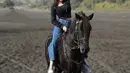 Saat berada di Bromo, sambil naik kuda, Eby mengenakan atasan jaket hitam crop senada dengan inner tanktopnya. Dipadukan celana denim panjang dan sneakers putih. [@kinen_bhy]