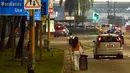 Seorang wanita membawa koper saat menuju Woodlands Checkpoint sebelum melintasi jalan lintas ke Malaysia di Singapura, Jumat (1/4/2022). Singapura dan Malaysia kembali membuka perbatasannya untuk semua pelancong yang divaksinasi lengkap. (Roslan RAHMAN/AFP)