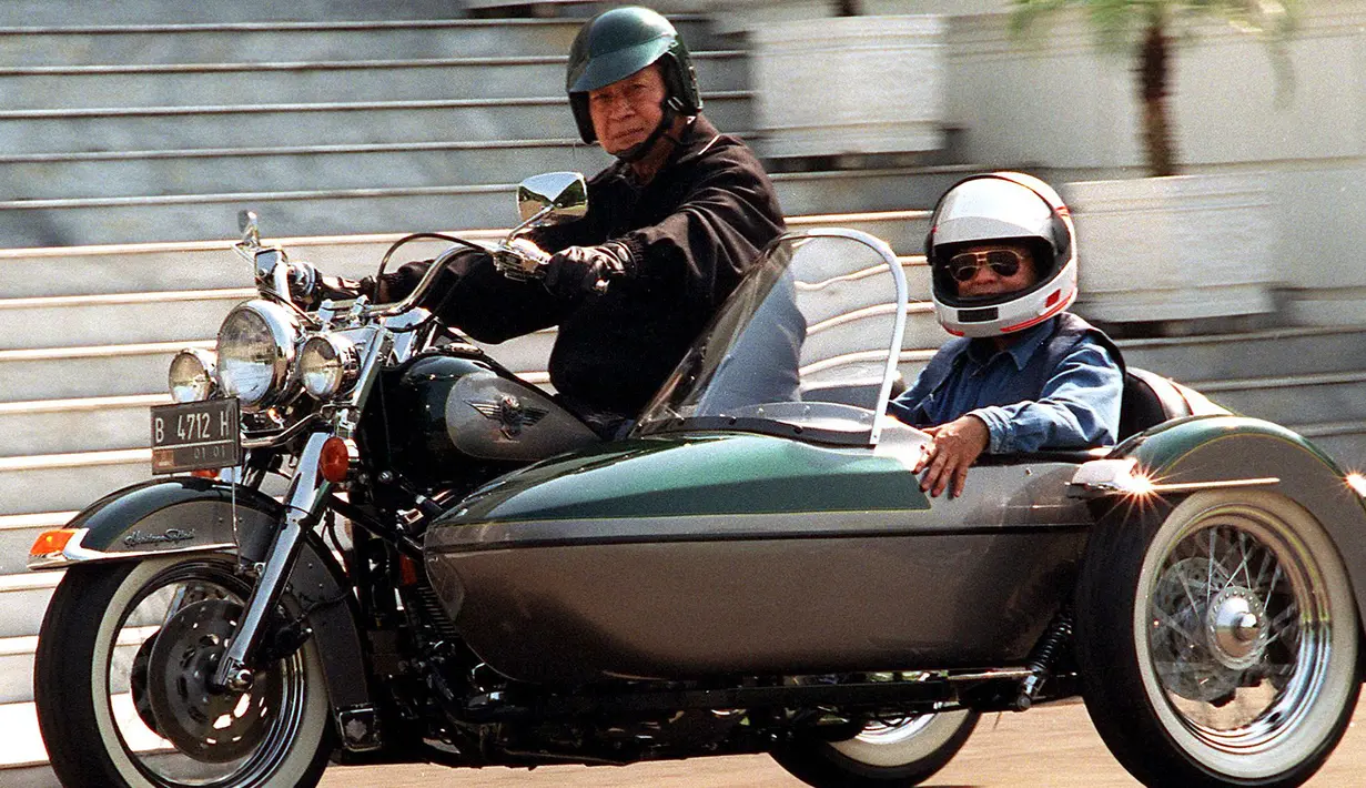 Presiden Soeharto dan Menteri Riset dan Teknologi BJ Habibie mengendarai Harley Davidson di halaman belakang Istana Merdeka, Jakarta pada 01 September 1996. (Photo by AGUS LOLONG / AFP)
