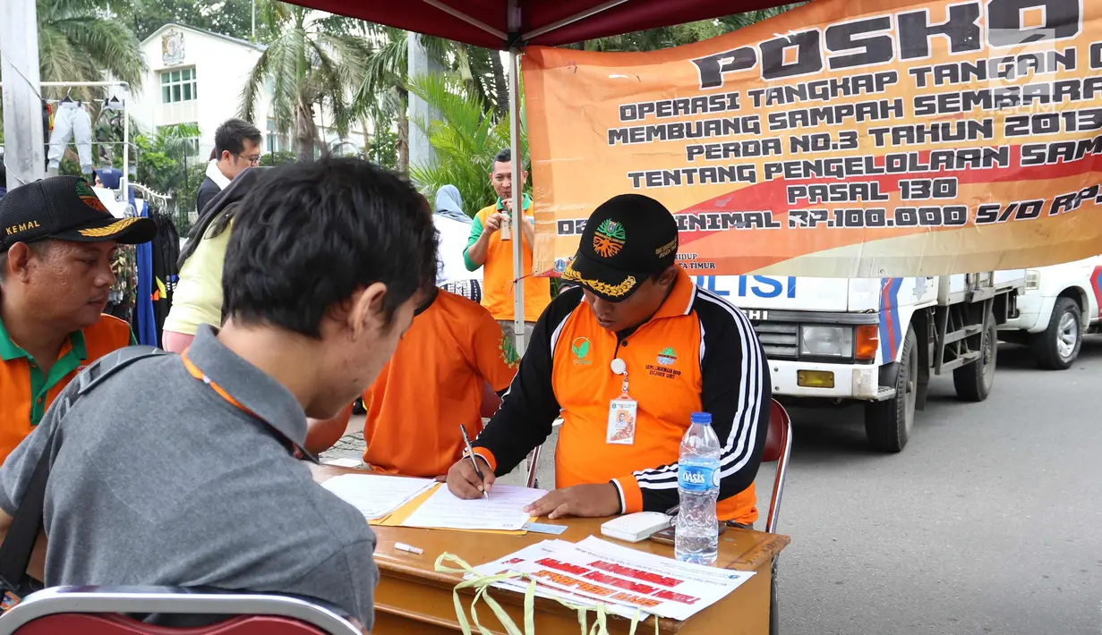 Petugas menindak seorang warga yang tertangkap tangan saat membuang sampah sembarangan di CFD, Jakarta, Minggu (28/1). Petugas juga memberi hukuman sosial atau denda minimal Rp 100.000. (Liputan6.com/Angga Yuniar)