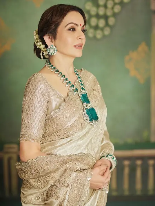 Mari beralih ke penampilan Nita Ambani dengan perhiasannya yang tak kalah memukau. Memadukan sari bernuansa emasnya, Nita memilih kalung zamrud hijau super besar, dipadukannya mengenakan anting dan gelang-gelang yang serasi. [Foto: Instagram/mickeycontractor]