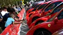 Pengunjung mengambil gambar mobil Ferrari yang dipamerkan saat perayaan ulang tahun Ferrari ke-70 di Corso Sempione di Milan, Italia (8/9). Dalam acara ini sekitar 500 mobil Ferrari dari berbagai tipe pamerkan. (AFP Photo/Miguel Medina)