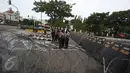 Tameng polisi diletakkan di belakang kawat berduri yang dipasang oleh petugas polisi di sekitar Istana Negara, Jakarta, Jumat (31/3). Kawat berduri tersebut dipasang untuk mengantisipasi ricuh aksi 31 Maret. (Liputan6.com/Immanuel Antonius)