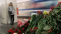 Seorang wanita melihat tumpukan bunga yang diletakkan di dekat lokasi bom meledak di stasiun kereta bawah tanah St. Petersburg, Rusia, Selasa (4/4). Dikabarkan 10 orang meninggal dalam tragedi tersebut. (AP Photo / Dmitri Lovetsky