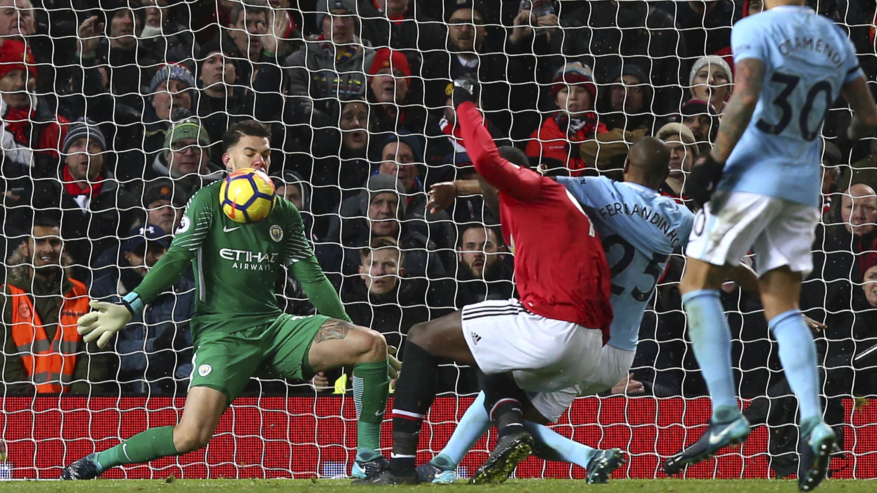 Kiper Manchester City, Ederson, menghalau bola tendangan dari striker Manchester United, Romelu Lukaku, pada laga Premier League di Stadion Old Trafford, Minggu (10/12/2017). (AP/Dave Thompson)