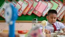Seorang siswa sekolah dasar menggunakan kipas angin portabel untuk menyejukkan ruangan kelas saat cuaca panas di Banda Aceh pada 15 Mei 2023. (AFP/CHAIDEER MAHYUDDIN)