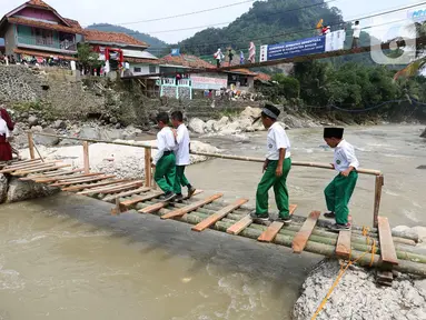 Siswa melintasi jembatan darurat berbahan bambu di Kampung Ciasahan, Desa Sukamaju, Kabupaten Bogor, Kamis (6/2/2020). Pembangunan kembali jembatan Ciasahan yang ambruk akibat banjir bandang pada Rabu (1/1) itu diharapkan mampu memulihkan aktivitas dan perekonomian warga. (merdeka.com/Arie Basuki)