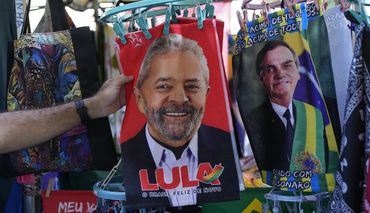 Seorang pembeli menyentuh handuk kecil bergambar mantan Presiden Brasil Luiz Inacio da Silva atau Lula di sebelah Presiden Brasil Jair Bolsonaro yang dijual menjelang pemilihan umum presiden di Rio de Janeiro, Brasil, 27 Juli 2022. Jair Bolsonaro diusung partai-partai populis kanan melawan tokoh kiri Luiz Inacio da Silva. (AP Photo/Silvia Izquierdo)