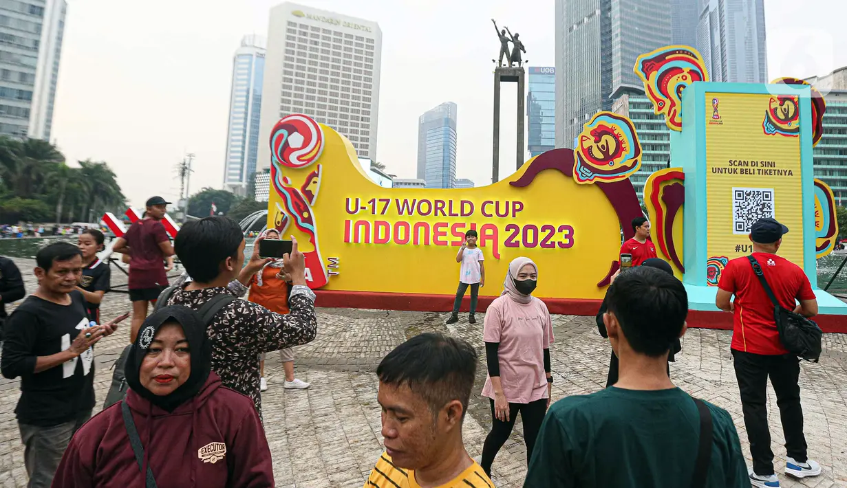 Masyarakat berswafoto dengan latar belakang papan promosi Piala Dunia U-17 2023 saat car free day (CFD) di kawasan Jalan Thamrin, Jakarta, Minggu (15/10/2023). Kegiatan tersebut dalam rangka promosi ajang Piala Dunia U-17 2023 di Indonesia. (Liputan6.com/Faizal Fanani)