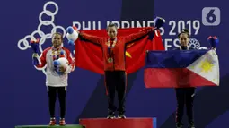 Lifter putri Indonesia, Lisa Setiawati (kiri) saat naik podium usai mendapatkan medali perak SEA Games 2019 cabang angkat besi nomor 45 kg di Stadion Rizal Memorial, Manila, Minggu (1/12/2019). Dirinya meraih perak dengan total angkatan 169 kg. (Bola.com/M Iqbal Ichsan)