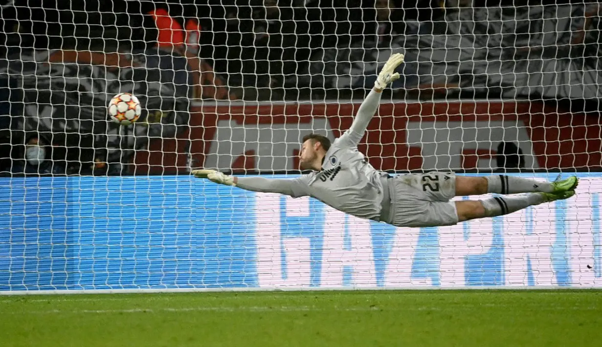 Penjaga gawang Club Brugge Simon Mignolet mencoba menepis bola tendangan pemain Paris Saint-Germain Lionel Messi pada pertandingan sepak bola Grup A Liga Champions di Parc des Stadion Princes, Paris, Prancis, 7 Desember 2021. Paris Saint-Germain menang 4-1. (Anne-Christine POUJOULAT/AFP)
