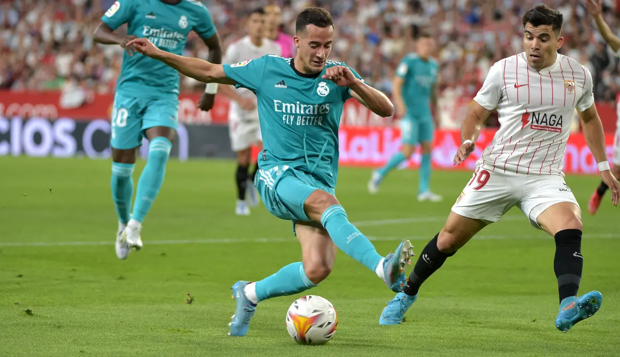 Pemain depan Real Madrid Lucas Vazquez (kiri) berebut bola dengan bek Sevilla Marcos Acuna pada lanjutan Liga Spanyol di stadion Ramon Sanchez Pizjuan, Senin (18/4/2022) dini hari WIB. Real Madrid sukses menaklukkan Sevilla 3-2. (CRISTINA QUICLER / AFP)