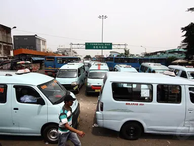 Warga melintasi angkutan umum yang sedang parkir di Terminal Senen, Jakarta, Senin (24/11/2014). (Liputan6.com/Faizal Fanani)