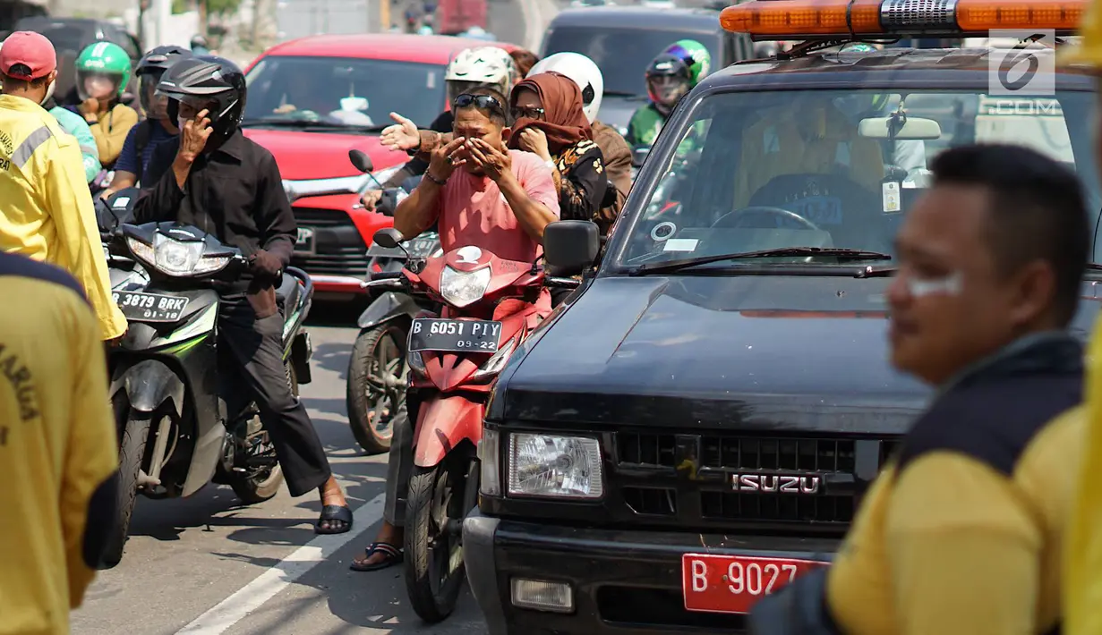 Petugas Sudin Bina Marga Jakarta Barat membagikan masker dan pasta gigi kepada pengendara motor di Jalan KS Tubun, Petamburan, Kamis (23/5/2019). Sisa gas air mata untuk membubarkan massa dalam kericuhan aksi 22 Mei masih terasa dan mengganggu aktvitas pengguna jalan (Liputan6.com/Immanuel Antonius)