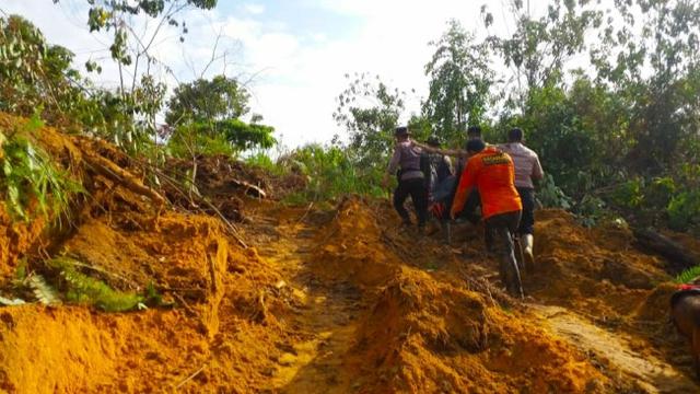Polisi dan Basarnas Pekanbaru mengevakuasi korban longsor di Desa Koto Ruang, Kabupaten Rokan Hulu.