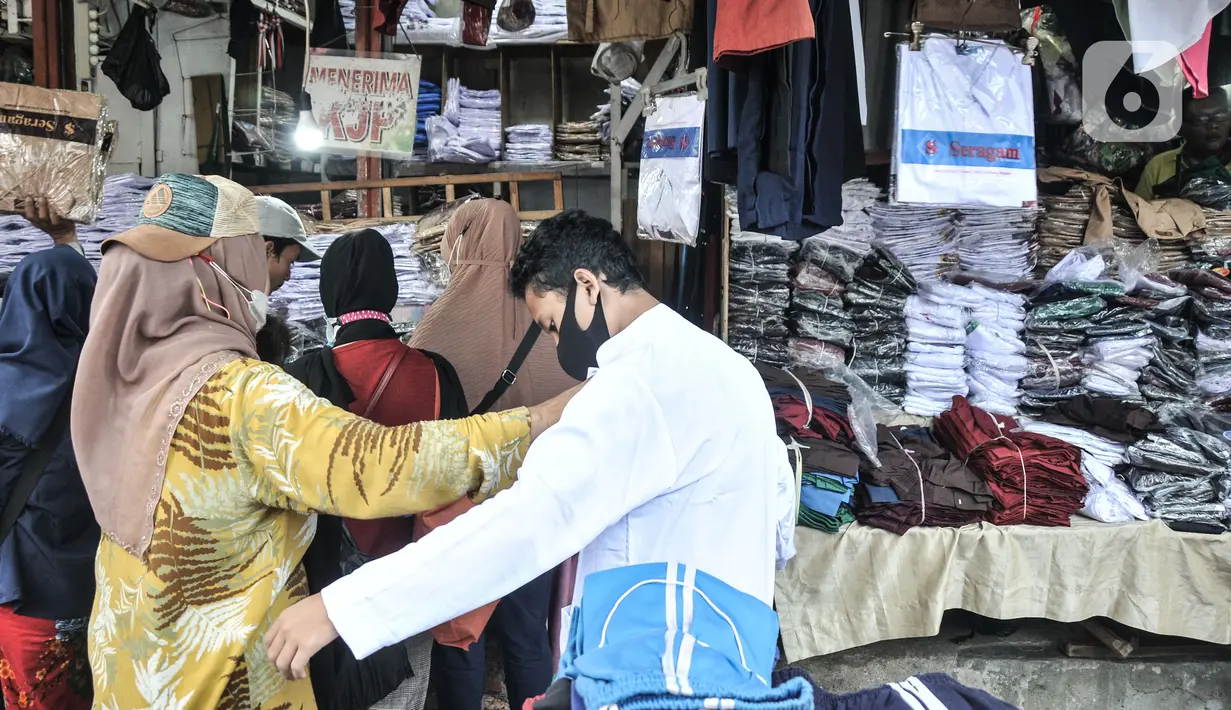 Seorang anak saat mencoba seragam sekolah di Pasar Mester Jatinegara, Jakarta Timur, Senin (3/1/2022). Salah satu pedagang mengungkapkan penjualan seragam sekolah mengalami peningkatan 50 persen seiring pemberlakuan PTM di Jakarta yang kembali digelar 100 persen. (merdeka.com/Iqbal S. Nugroho)