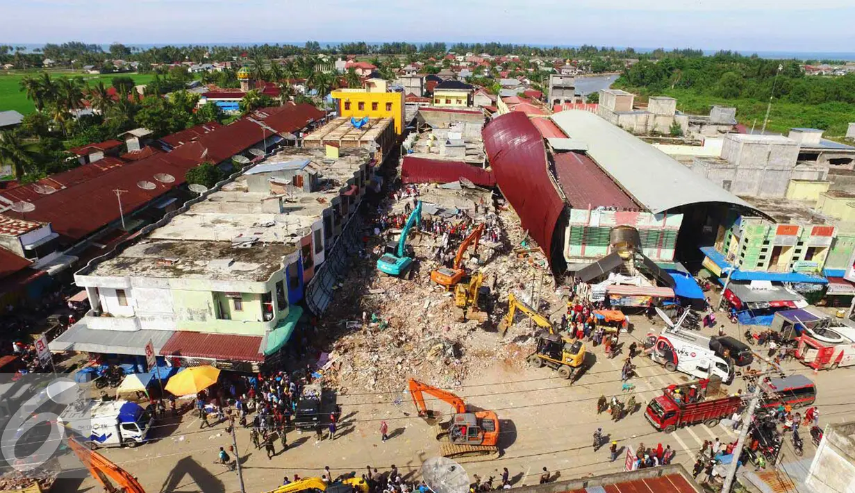 Pemandangan dari atas saat sejumlah eskavator dikerahkan untuk mengangkat puing-puing di Pasar Meureudu, Pidie Jaya, Aceh yang runtuh akibat gempa, Kamis (8/12). Dikabarkan korban meninggal sudah mencapai 102 orang. (Liputan6.com/Angga Yuniar)