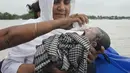 Diluwara Begum, seorang bidan, menggendong bayi yang baru lahir setelah membantu persalinannya di atas perahu di atas Sungai Brahmaputra, di negara bagian Assam, India timur laut, Rabu, 3 Juli 2024. (AP Photo/Anupam Nath)