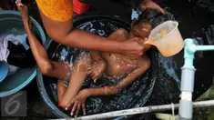 Indrawan saat dimandikan neneknya di Kampung Katimaha, Bekasi, Jawa Barat, (11/7). Indrawan divonis mengalami kelainan pada tulang belakang saat diperiksa di RSUD Cibitung. Puskesmas Sukaraya. (Liputan6.com/Gempur M Surya)