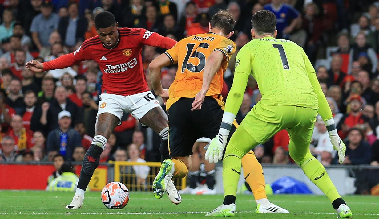 Pemain Manchester United, Marcus Rashford (kiri) berusaha melewati pemain Wolverhampton, Craig Dawson (tengah) pada laga pekan pertama Liga Inggris 2023/2024 di Old Trafford, Manchester, Selasa (15/08/2023) WIB. (AFP/Lindsey Parnaby)