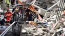 Tim penyelamat dibantu anjing pelacak mencari para korban di puing-puing gedung apartemen lima lantai yang runtuh di kota wisata Los Cristianos, Tenerife, Spanyol, Kamis (14/4). 9 orang terjebak di dalam reruntuhan gedung tersebut. (Desiree MARTIN/AFP)