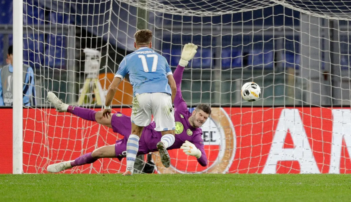 Kiper Celtic, Fraser Forster melakukan penyelamatan dari serangan pemain Lazio, Ciro Immobile pada matchday keempat Grup E Liga Europa 2019 di Stadion Olympico, Kamis (7/11/2019). Celtic mengalahkan Lazio 2-1 untuk kemudian melaju ke babak 32 besar. (AP/Gregorio Borgia)