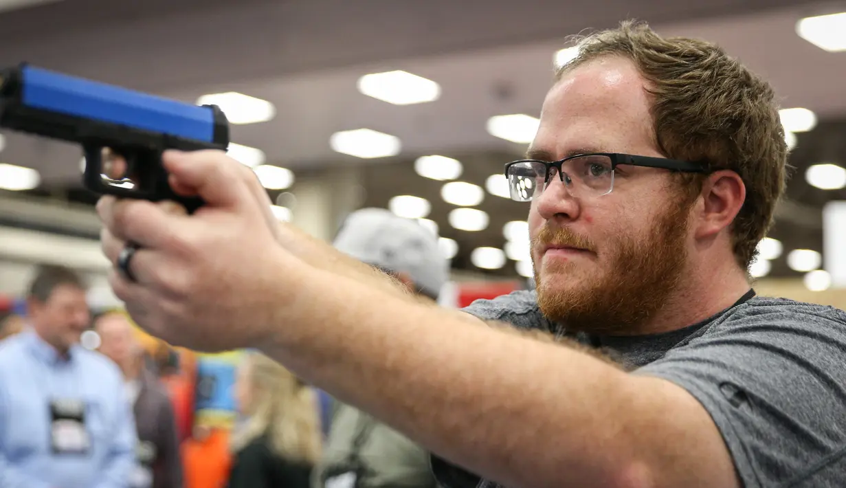 Seorang pria menjajal pistol di Kay Bailey Hutchison Convention Center saat konvensi tahunan NRA, Texas (6/5). Acara pameran senjata ini dihadiri sekitar 70.000 peserta. (AFP/Loren Elliot)