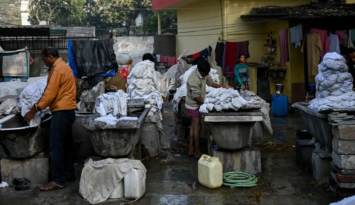 Tukang cuci mencuci pakaian di binatu terbuka, yang secara lokal disebut 'Dhobi Ghat' di New Delhi, India pada 14 Maret 2022. Dhobi Ghat adalah tempat yang menyediakan layanan cuci dengan cara tradisional. (Money SHARMA / AFP)