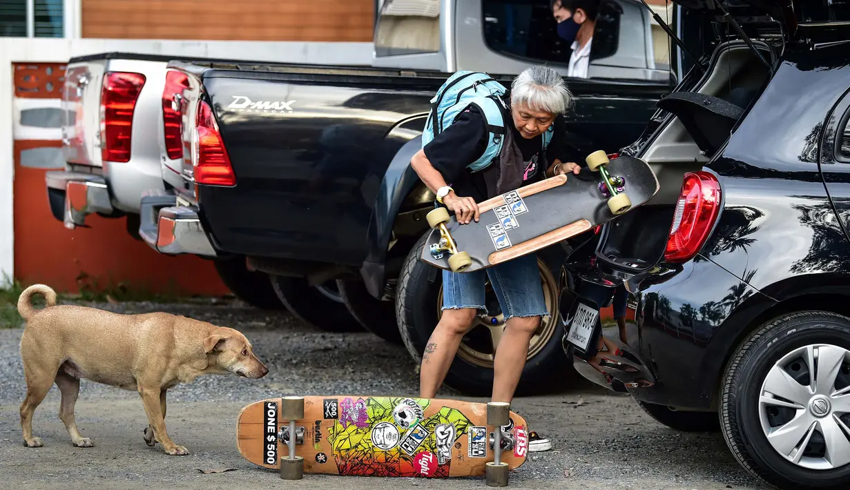 Longboarder dan penderita kanker Nongluck Chairuettichai, juga dikenal sebagai Jeab, mengeluarkan papan skatenya di Bangkok, 9 September 2020. Melaju di jalan raya yang kosong, kegiatan ini dilakukan sebagai jalan pemulihan dari kanker payudara yang dideritanya (Lillian SUWANRUMPHA/AFP)