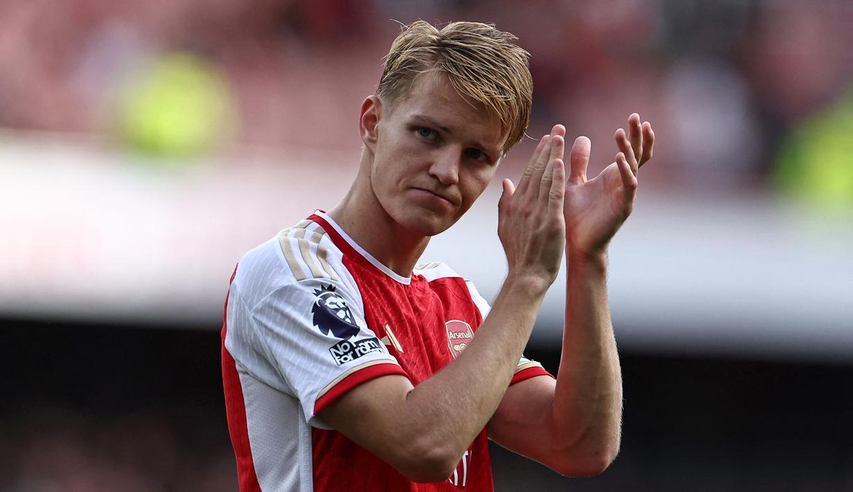 Kapten Arsenal, Martin Odegaard memberikan tepuk tangan saat berjalan meninggalkan lapangan setelah laga lanjutan Liga Inggris 2023/2024 melawan Tottenham di Emirates Stadium, London, Inggris 24 September 2023. Arsenal belum lama ini memperpanjang kontrak Odeegard. Meski kontrak awalnya baru habis pada 2025, The Gunners tak ragu untuk memperpanjang kontrak sang pemain hingga 2028. Kini, pemain asal Norwegia tersebut diketahui memiliki gaji sebesar 240 ribu pounds per pekan atau menempati urutan ketiga kapten bergaji tertinggi di Liga Inggris. (AFP/Henry Nicholls)