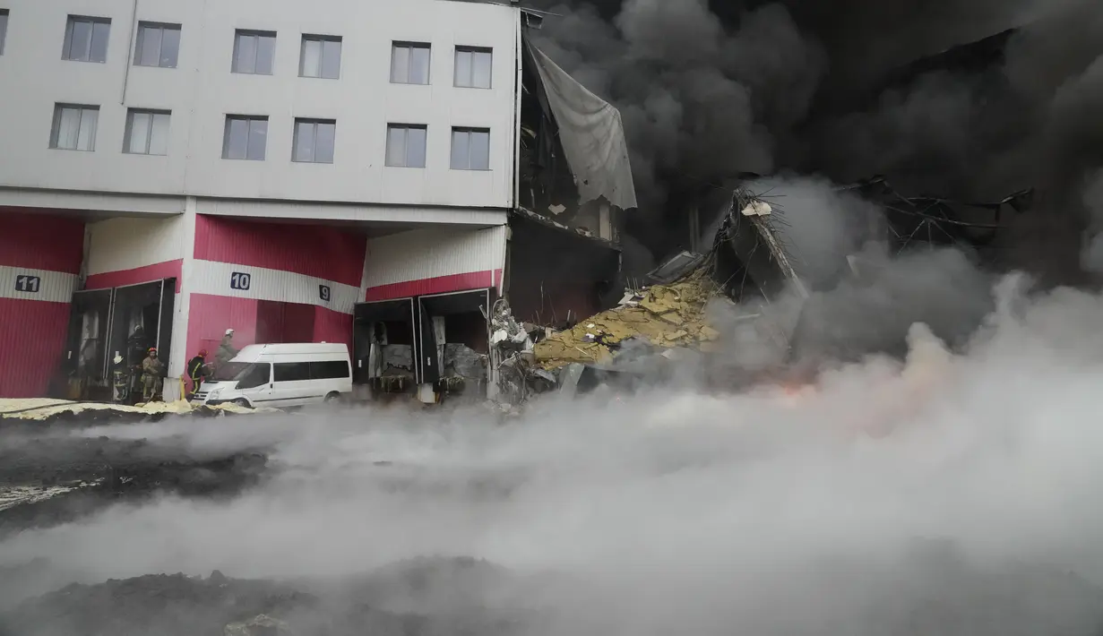 Petugas pemadam kebakaran berusaha memadamkan api di pusat logistik yang rusak setelah penembakan di Kiev, Ukraina, Kamis (3/3/2022). Rusia telah meluncurkan serangan jarak jauh ke Ukraina, menghantam kota dan pangkalan dengan serangan udara atau penembakan. (AP Photo/Efrem Lukatsky)