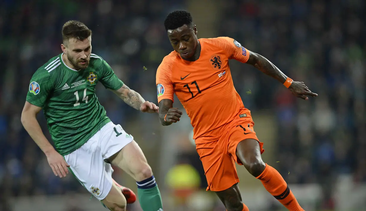 Gelandang Belanda, Quincy Promes, beradu cepat dengan gelandang Irlandia Utara, Stuart Dallas, pada laga Kualifikasi Piala Eropa 2020 di Windsor Park, Belfast, Sabtu (16/11). Kedua negara bermain imbang 0-0. (AFP/Mark Marlow)