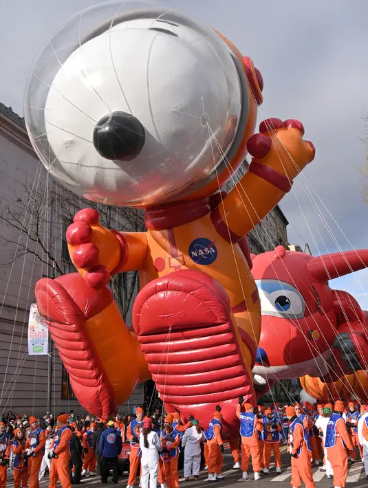 Peserta menerbangkan balon  Astronaut Snoopy dalam parade perayaan Hari Thanksgiving di kawasan Sixth Avenue, New York, Kamis (28/11/2019). Parade yang membelah jalanan kota New York ini selalu ditunggu setiap tahunnya. (Theo Wargo/Getty Images/AFP)