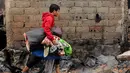 Seorang warga menyelamatkan beberapa barang - barang yang masih bisa digunakan. (Liputan6.com/Andrian M Tunay)