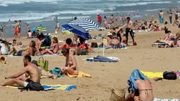 Orang-orang berjemur di pantai Port Vieux, (Old Seaport) di Biarritz, barat daya Prancis, (19/4). Suhu di Prancis barat daya telah mencapai 27 derajat Celcius (80,6 Fahrenheit). (AP Photo / Bob Edme)