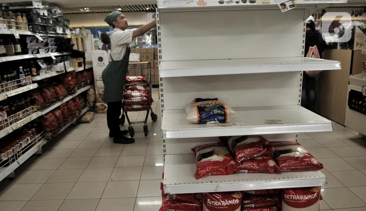 Aktivitas pekerja di dekat rak beras yang kosong di sebuah pusat perbelanjaan di Kelapa Gading, Jakarta, Senin (2/3/2020). Warga berbondong-bondong membeli bahan-bahan pokok hingga masker dan hand sanitizer setelah dua warga Depok positif terinfeksi virus corona. (merdeka.com/Iqbal S Nugroho)