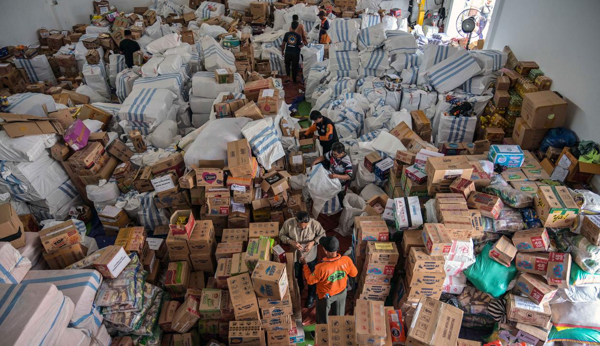 Bantuan yang akan disalurkan berupa makanan, alat kebersihan, alat kesehatan, obat-obatan, selimut, dan alat masak yang sangat dibutuhkan oleh warga di lokasi bencana. Tampak dalam foto, para relawan mengemasi perlengkapan untuk dikirimkan ke daerah-daerah terdampak banjir di Badan Penanggulangan Bencana Daerah (BPBD) Sidoarjo, Provinsi Jawa Timur, pada Jumat 5 Desember 2025. (JUNI KRISWANTO/AFP)